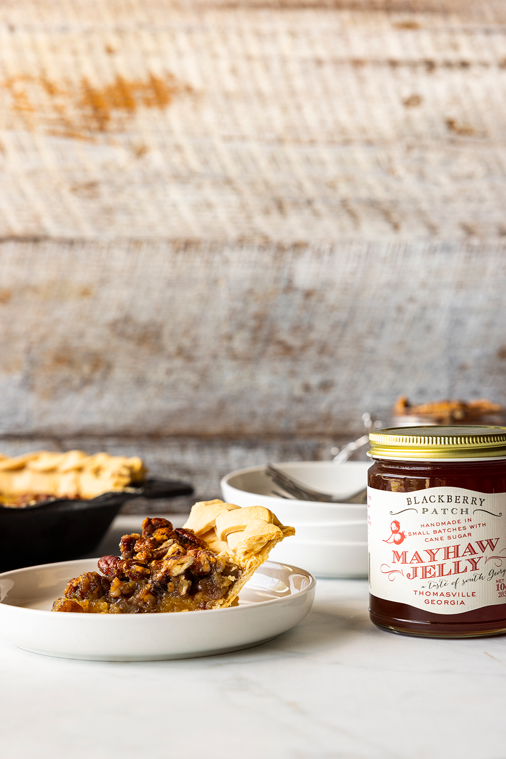 Image of Mayhaw Pecan Pie on a plate with jar of Mayhaw Jelly next to it. 