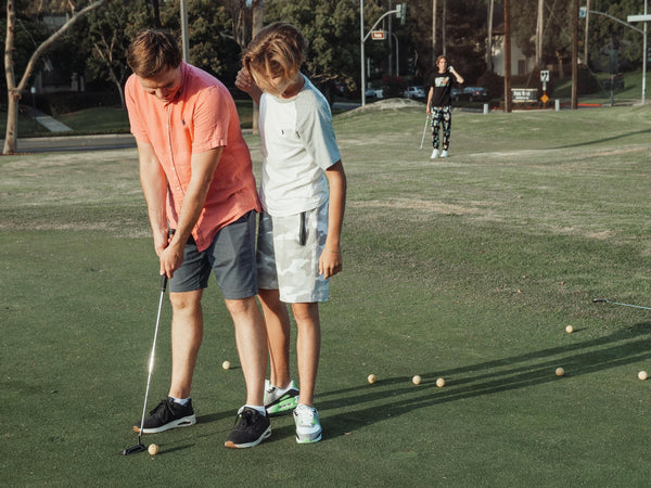 A golf pro teaching kids a fundamental of making a golf shot