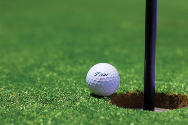 A golf ball near the cup in a golf course in San Diego