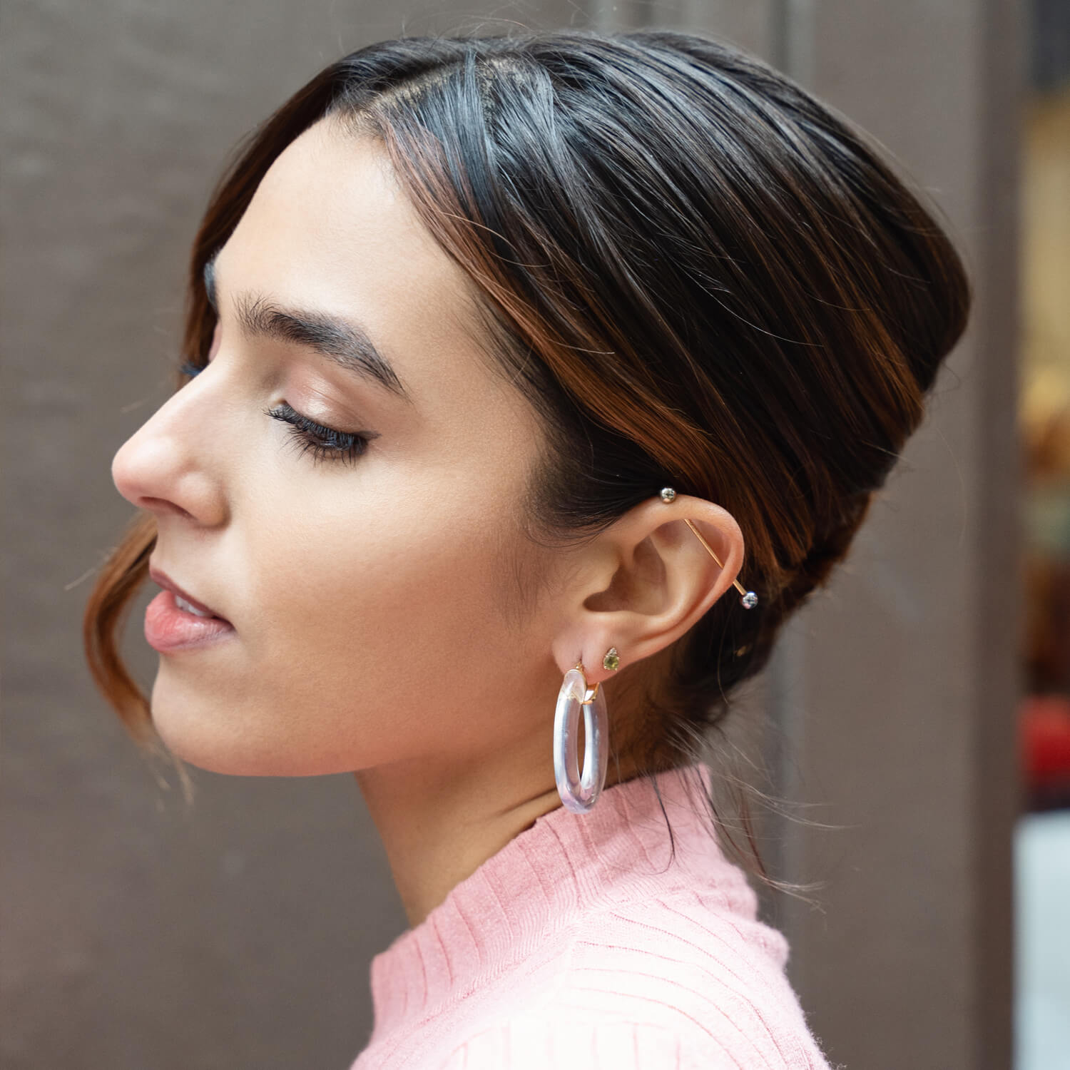 Fashionable woman with long hair in ponytail hairstyle wearing trendy hoop  earrings, white turtleneck sweater, posing in street of European city.  Copy, empty space for text Stock Photo | Adobe Stock