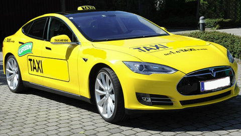 Yellow Tesla Taxi cab parked on a cobble stone driveway