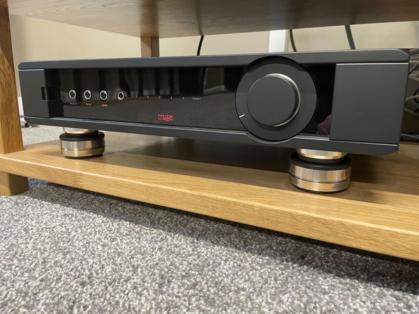 A photo of the Rega Elicit Mk5 Integrated Amplifier with IsoAcoustics OREA Bronze audio isolation pucks underneath its four corners.