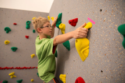 Boy rock climbing on a Traverse Wall using marked hand holds