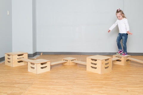 Girl walking across planks in balance boxes