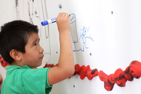 Boy drawing on a Discovery Dry-Erase climbing wall by Everlast Climbing