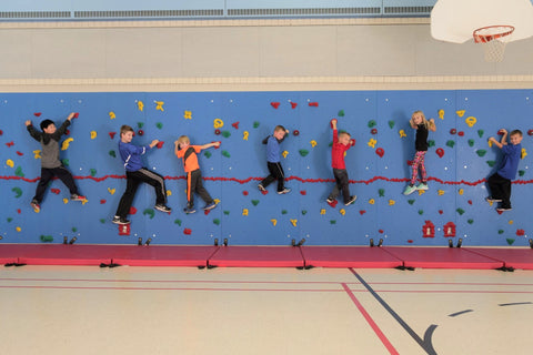 Children climbing on a K-12 school Traverse Wall by Everlast Climbing