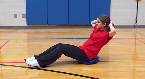 Girl performing crunches on a balance disc