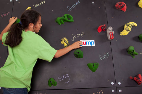 Girl climbing and spelling words on a Discovery Blackboard Climbing Wall by Everlast Climbing