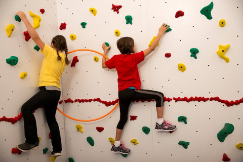 Girls rock climbing on a traverse wall linked with a hoop