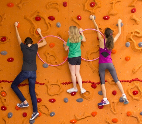 Girls rock climbing linked by hoops to work on cooperation and communication