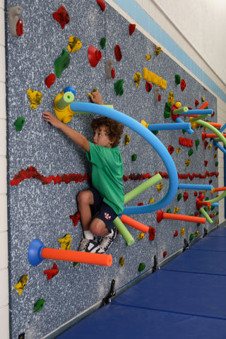 Boy climbing through the climbing wall challenge course