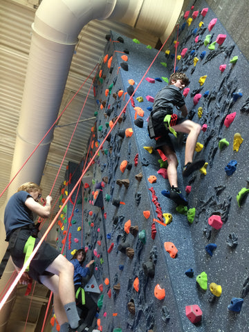 Students being lowered down from the top of the climbing wall after reaching the top