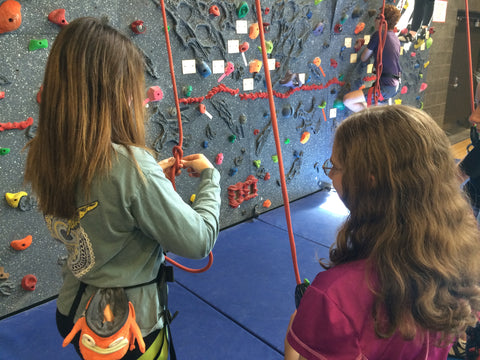 Girl tying a figure eight knot before rock climbing