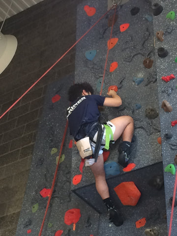 Boy trying to climb over a roof feature on a top rope climbing wall