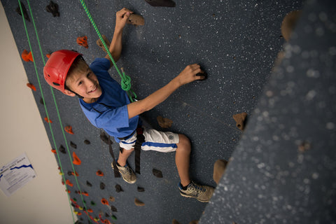 Boy rock climbing on a top rope wall in a k12 school