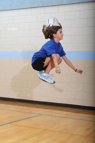Girl performing tuck jump exercise to build muscular strength