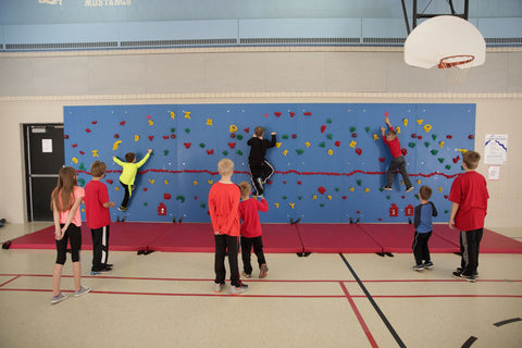 Children participating in a relay race on a Chroma Traverse Wall by Everlast Climbing