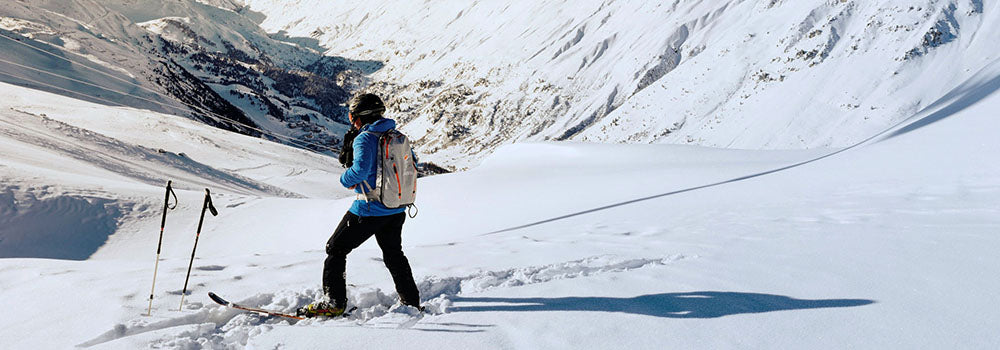 Eine Person steht auf Skiern auf einem verschneiten Berg