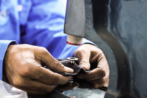 A worker pressing buttons into denim