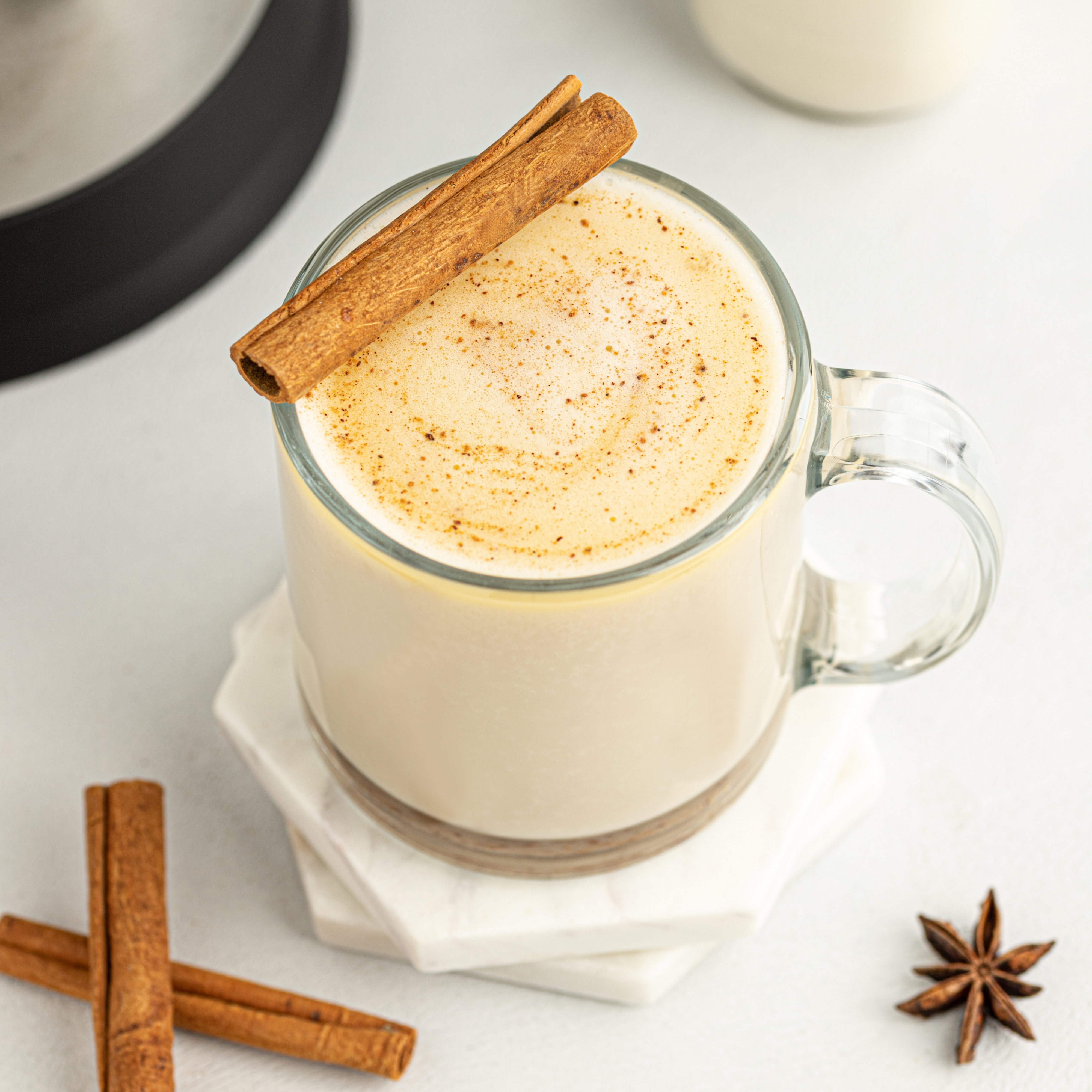 vegan hot buttered rum in a glass mug garnished with a cinnamon stick