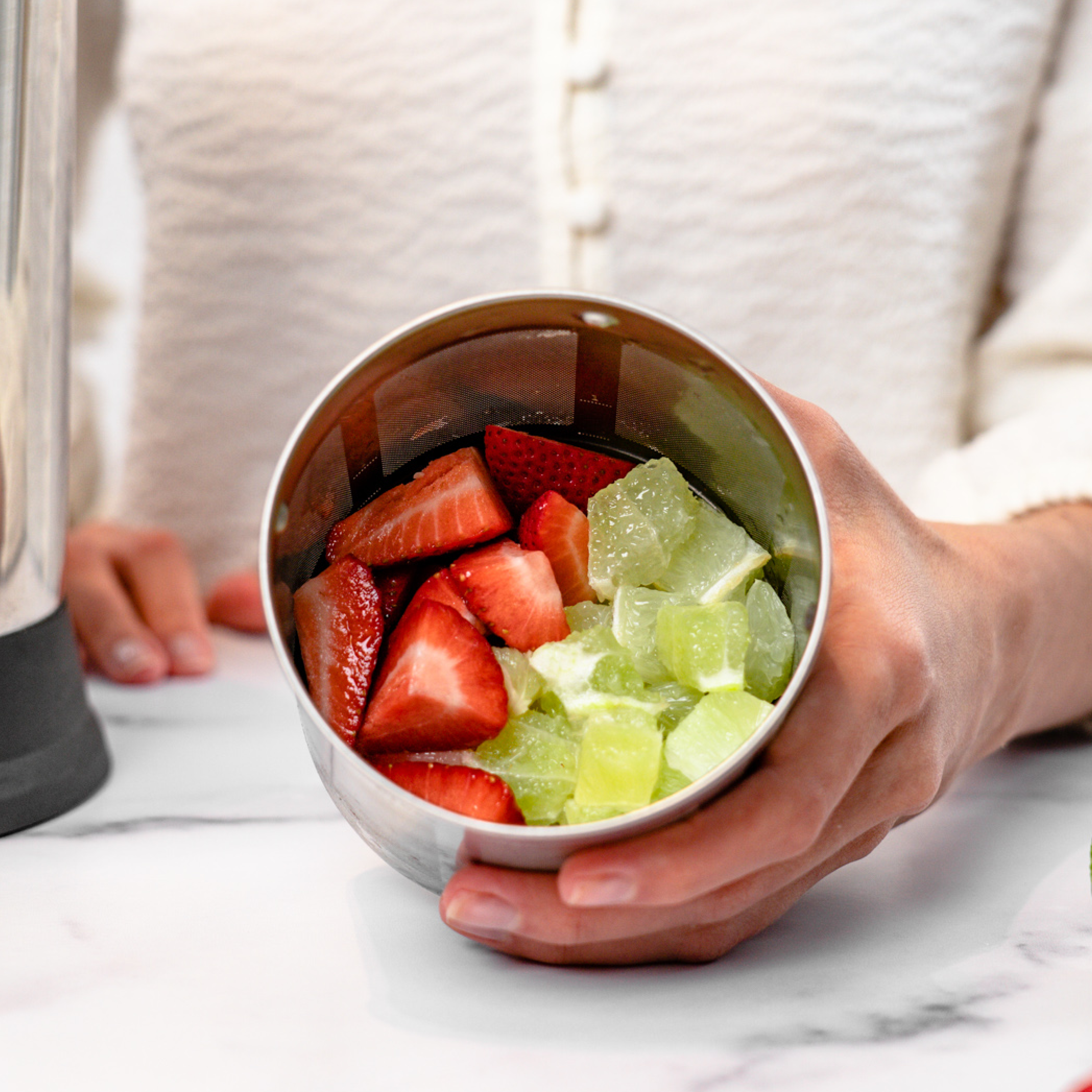 person holding filter basket full of strawberries and limes