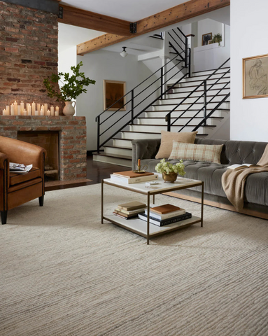 A beige rug, a grey couch, and a brown leather chair