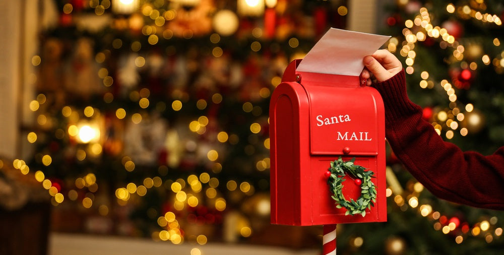 Child's hand puts a letter to santa claus in the christmas mailbox