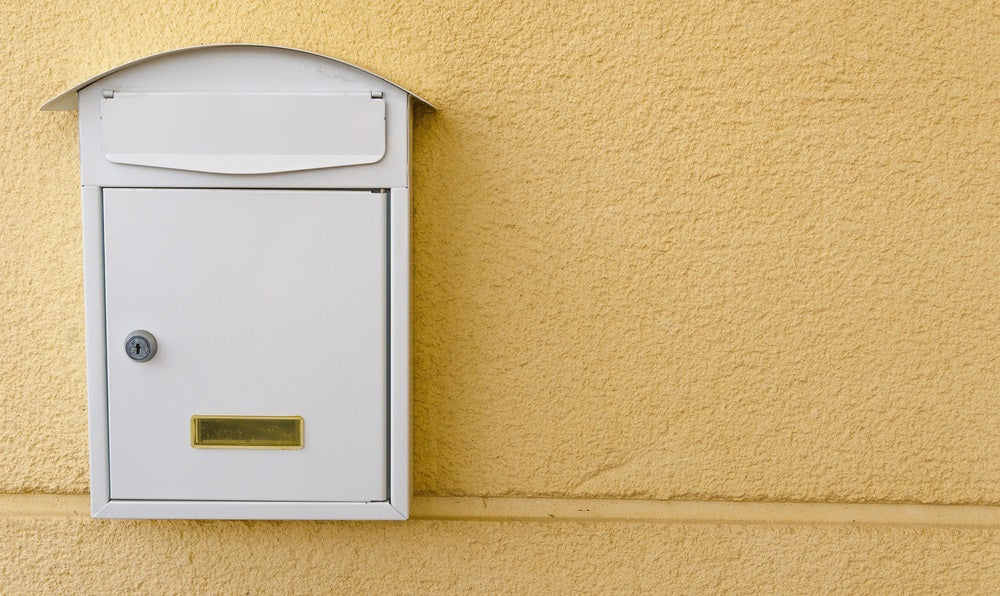 Metallic mailbox painted in white over a yellow background