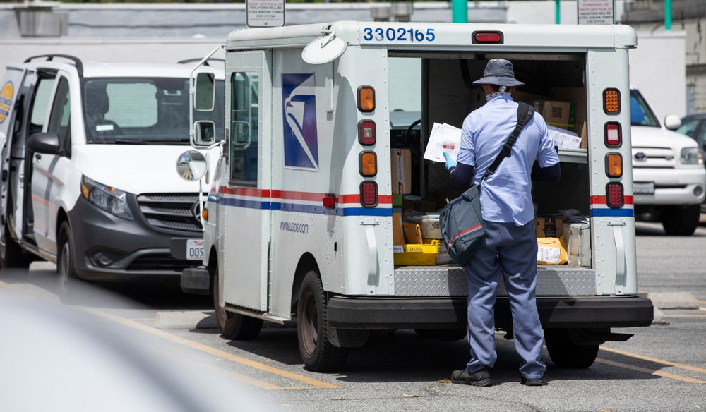 mail truck and postal carrier make a delivery