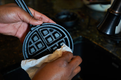 Wiping the Cast Iron Stuffed Waffle Iron with a paper towel