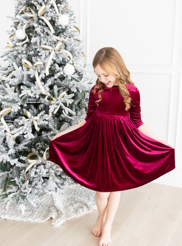 cranberry velvet twirl dress in front of Christmas tree