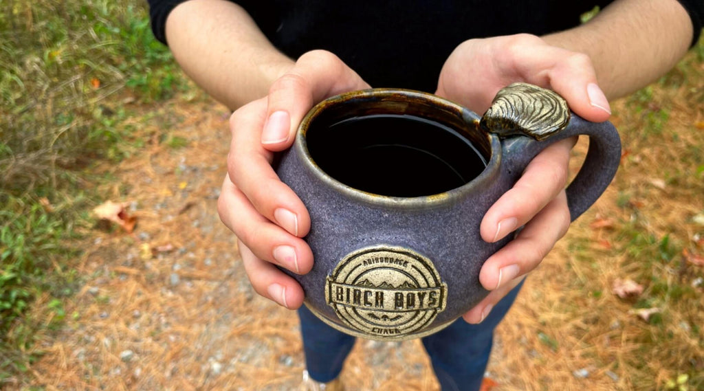 A rich brew of Chaga tea in a purple mug, held by a woman outside