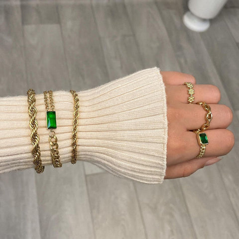 Woman's arm wearing a white jump with multiple bracelets and multiple rings being worn