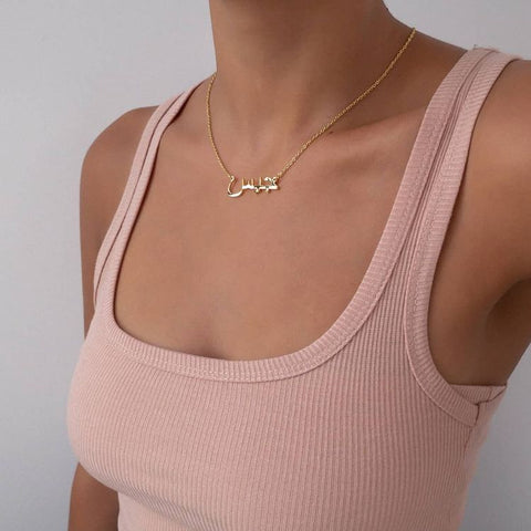 Personalisierte Schmuckgeschenke – Halskette mit arabischem Namen an einer Frau, die ein rosa Oberteil trägt