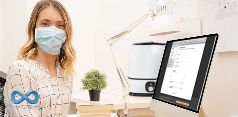 girl in a medical mask sits in front of a computer monitor