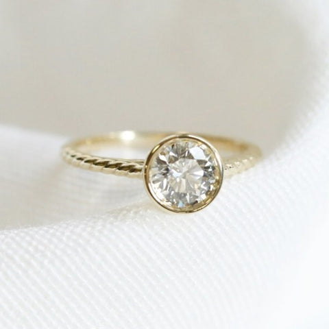 bezel set round diamond engagement ring with a yellow gold setting and rope band