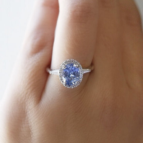 oval blue sapphire engagement ring with a diamond halo and baguette diamonds on the sides set in white gold