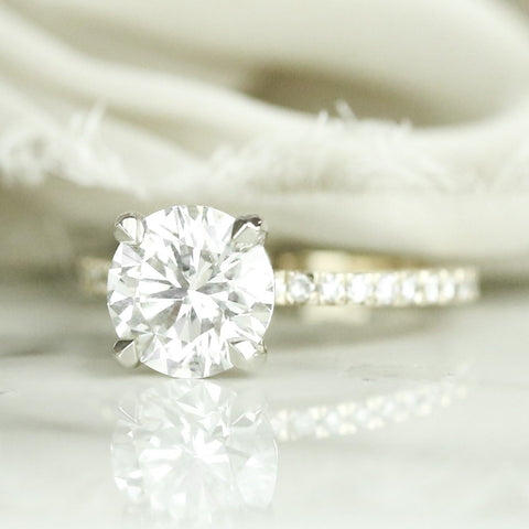 round diamond engagement ring set with four claw prongs and diamonds on the band