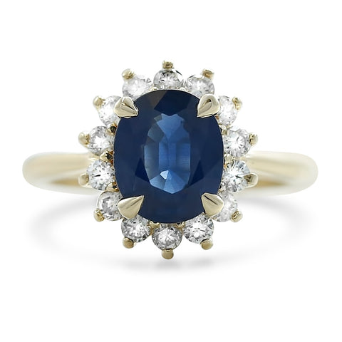 oval blue sapphire engagement ring with a white diamond halo and yellow gold band and setting