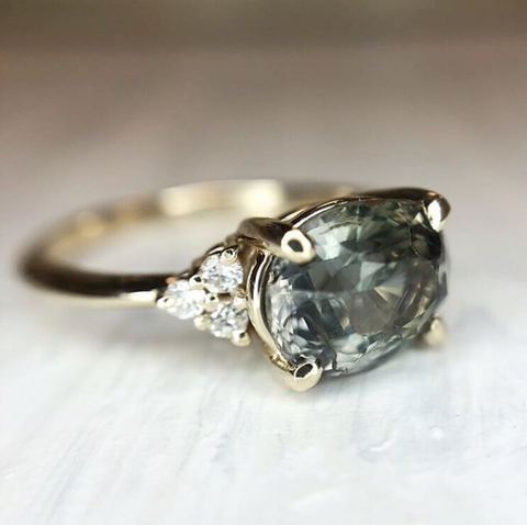 light green oval sapphire engagement set east-west with yellow gold band and diamonds
