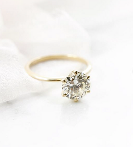 round solitaire diamond engagement ring with a thin yellow gold band 