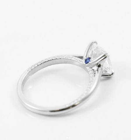 white gold and diamond custom engagement ring with a hidden sapphire eon the side of the ring