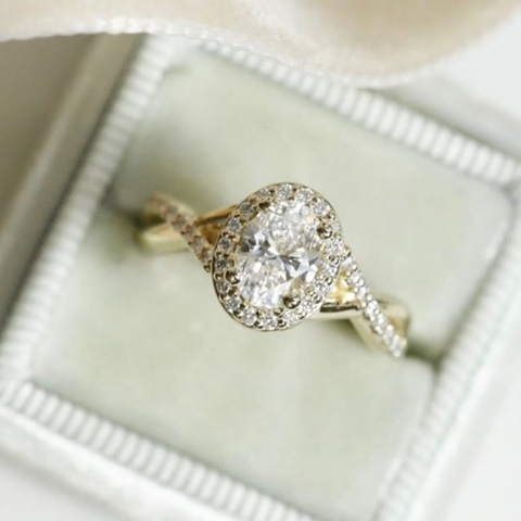 Yellow gold oval prong set diamond engagement ring with diamond halo and intricate diamond band