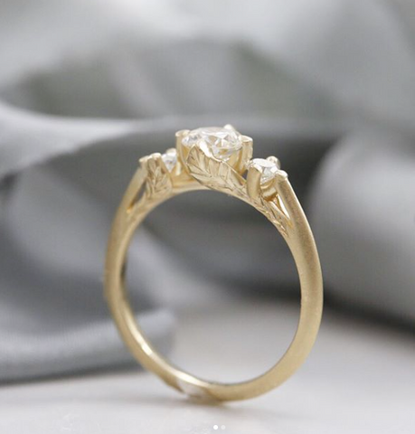 custom diamond engagement ring with leaf details on the side of the yellow gold ring