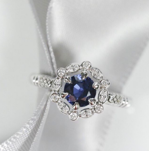 Round blue classic sapphire custom engagement ring with a unique diamond halo set in white gold