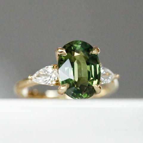green oval sapphire engagement ring with pear diamond side stones