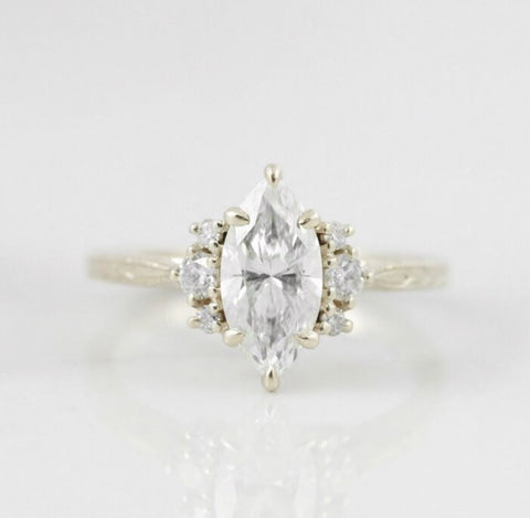 marquise diamond custom engagement ring with three diamonds on each side set in 14k yellow gold with an engraved band