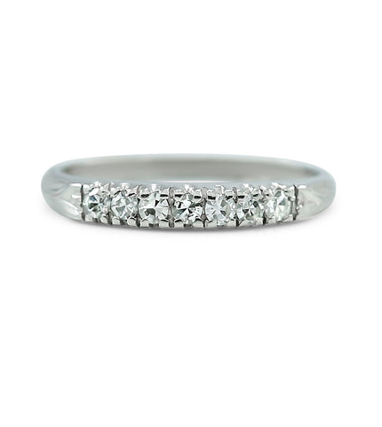 platinum estate wedding band with prong set diamonds and hand engraving on both sides of the band