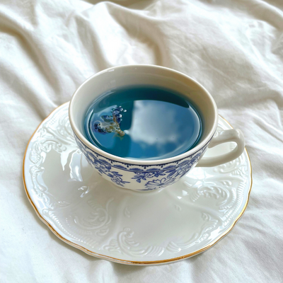 Butterfly pea flower blue tea in a white teacup with cloud reflected in tea