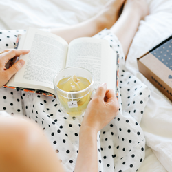Person reading a book and drinking caffeine-free tea